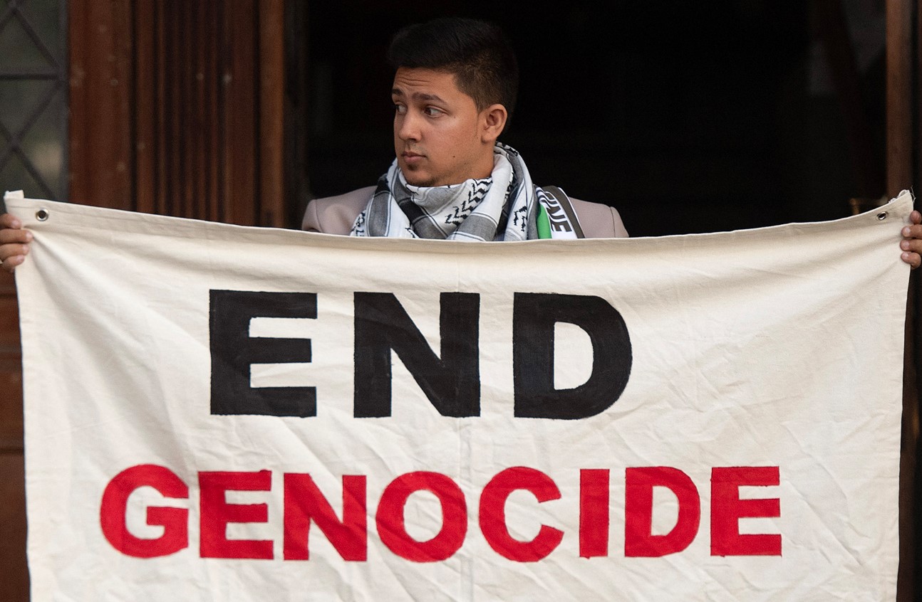 South Africa accuses Israel of breaching Genocide Convention - A man holds a banner as people gather during an interfaith protest in solidarity with Palestinian people outside the High Court in Cape Town on January 11, 2024. (Photo: /Rodger Bosch/AFP) 