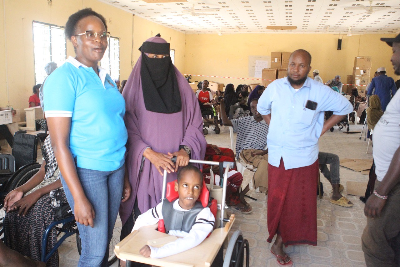 NCPWD's Winfred Mbugua (left) comforts a child living with disability in Garissa after donating assistive devices at Garissa Primary School on Friday, June 28, 2024. (Photo Issa Hussein)