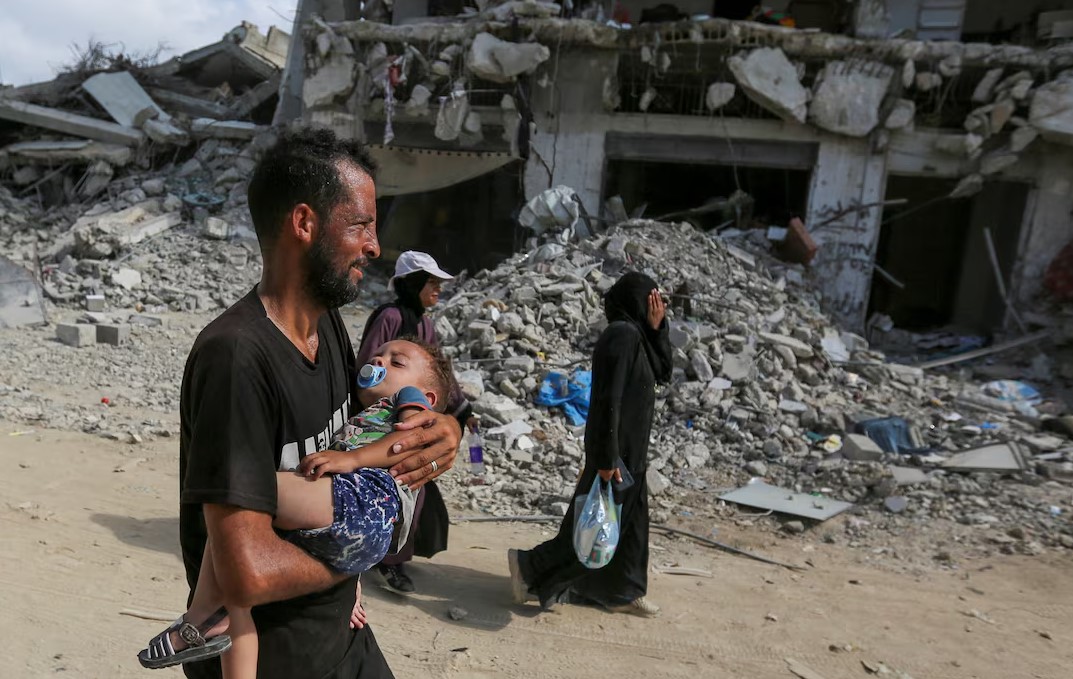 A Palestinian man carries a child, as Palestinians make their way to return to the eastern side of Khan Younis after Israeli forces pulled out from the area following a raid, amid the Israel-Hamas conflict, in Khan Younis, in the southern Gaza Strip July 30, 2024. (Photo: REUTERS/Hatem Khaled)