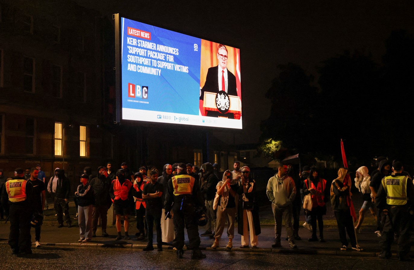 People stand under a billboard showing Britain's Prime Minister Keir Starmer during a protest outside a mosque in Liverpool, Britain, August 2, 2024. (Photo: REUTERS/Hollie Adams)