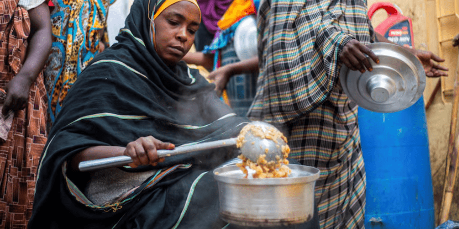 Sudan's warring sides target local aid volunteers fighting famine - A Sudanese woman from a community kitchen run by local volunteers distributes meals for people who are affected by conflict and extreme hunger and are out of reach of international aid efforts, in Omdurman, Sudan, August 22, 2024. (Reuters)