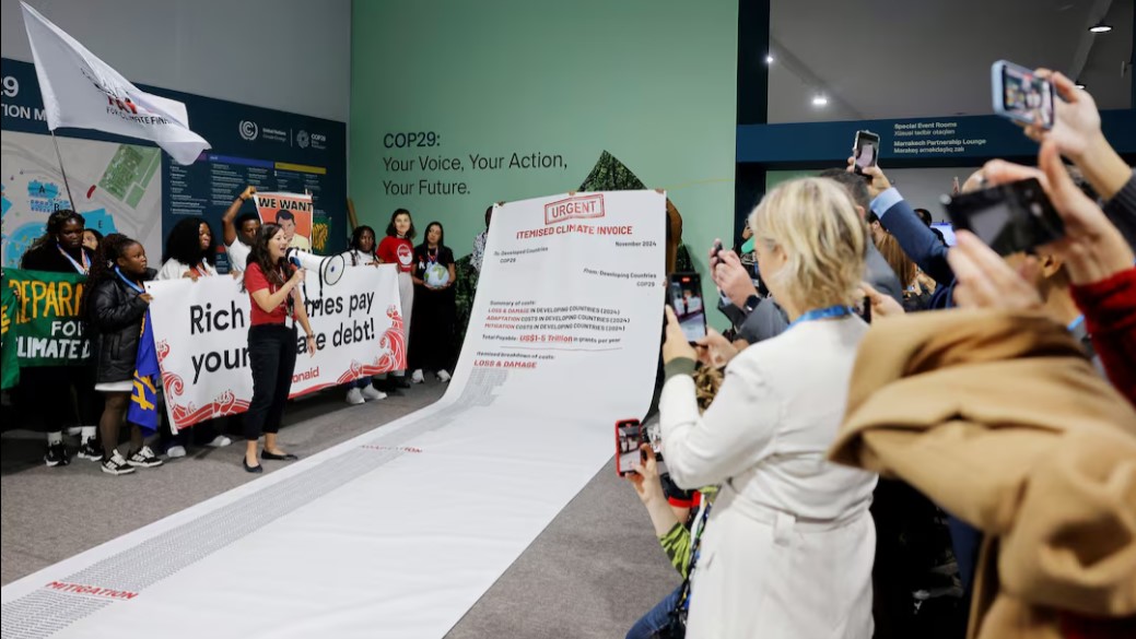 Refugees decry lack of adequate climate funding in most vulnerable regions - Activists display a 10-metre-long climate invoice directed at developed countries at a protest during the COP29 in Baku, Azerbaijan on November 14, 2024. (Photo: REUTERS/Maxim Shemetov)