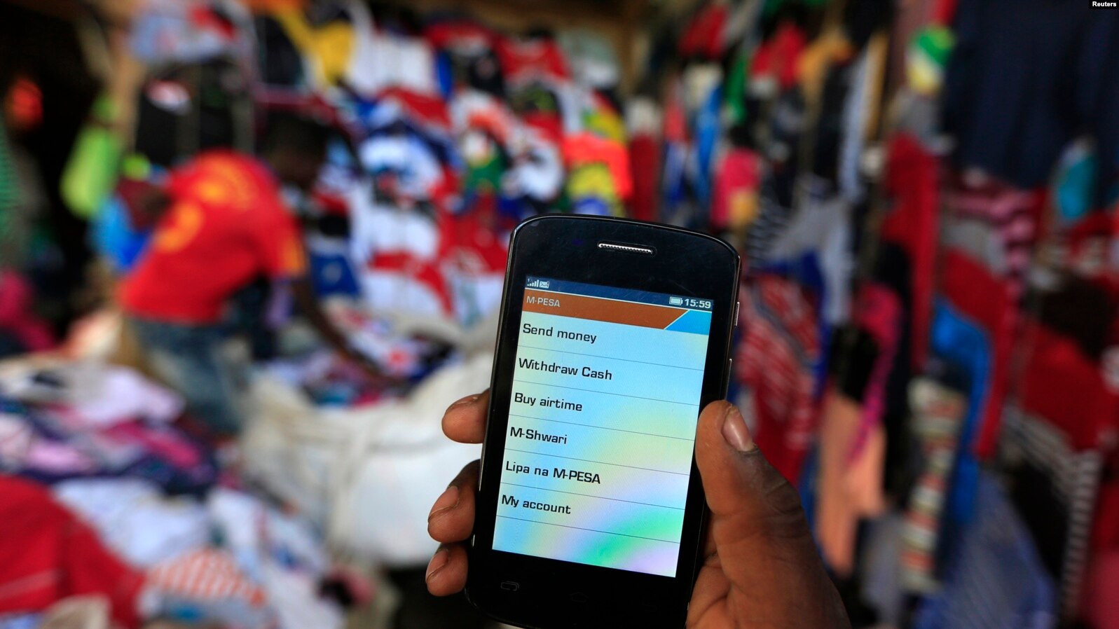 Kenya's mobile money transactions hit record Sh6.5 trillion - A man holds up his mobile phone at an open-air market in Kibera in Kenya's capital, Nairobi. (Photo: Reuters)