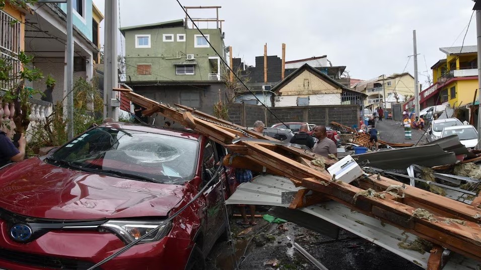 Mayotte authorities race to help cyclone survivors amid fear of hunger and disease - People stand near a damaged car covered by debris on December 16, 2024, in the aftermath of Cyclone Chido, in Mayotte, France. (Photo: Ministere de l’Interieur/Handout via REUTERS)