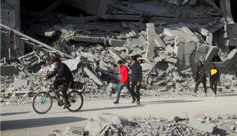 Israel, Hamas ceasefire accord followed by airstrikes on Gaza, residents say - Palestinians in Gaza City on January 15, 2025 walk among the rubble of houses destroyed in previous Israeli strikes, amid ceasefire negotiations with Israel. (Photo: REUTERS/Mahmoud Issa)