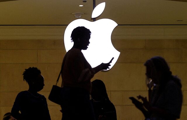 Apple users urged to update their phones after major security breach - A woman uses an iPhone mobile device as she passes a lighted Apple logo at the Apple store at Grand Central Terminal in New York City, U.S., April 14, 2023. (Photo: REUTERS/Mike Segar)