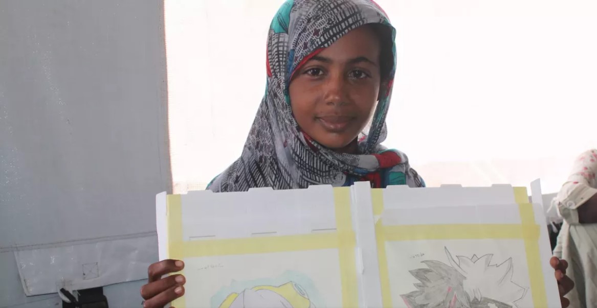 Families find safety in Arab 6 camp amid uncertainty in Sudan - Salawa, 17, holds up two drawings in a child-friendly space at a camp for internally displaced people in Kassala state, Sudan. (Photo: UNICEF/Nakibuuka)