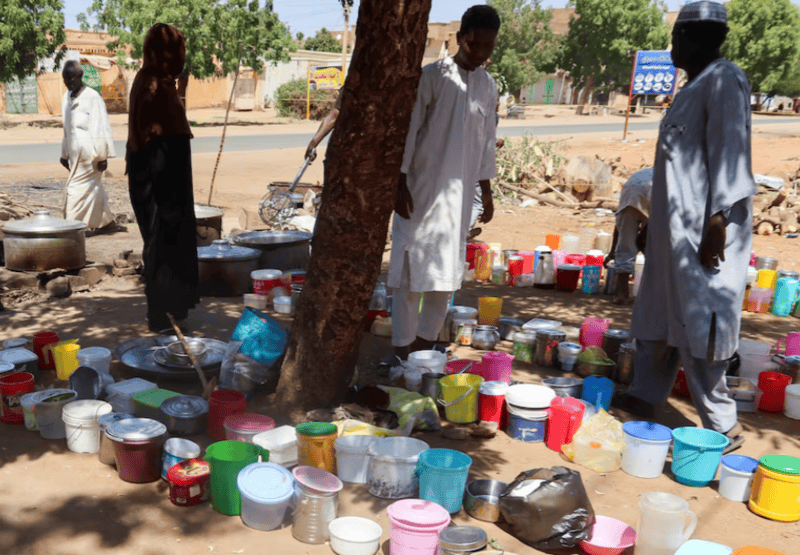 Sudan conflict: Latest in a history of coups, wars and instability - Sudanese men stand next to empty containers in front of "Takaya" the charity restaurant and a community kitchen, that helps the needy Sudanese in Omdurman areas recently controlled by army during the conflict and war, during the holy month of Ramadan in the state of Khartoum, Sudan March 14, 2025. REUTERS