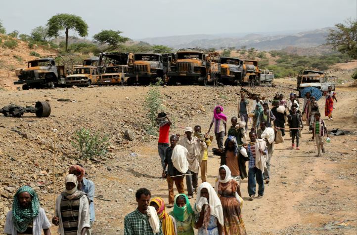 Foreign missions call for urgent cessation of hostilities in Northern Ethiopia - Villagers return from a market to Yechila town in south central Tigray walking past scores of burned vehicles, in Tigray, Ethiopia, July 10, 2021. (Photo: REUTERS/Giulia Paravicini)